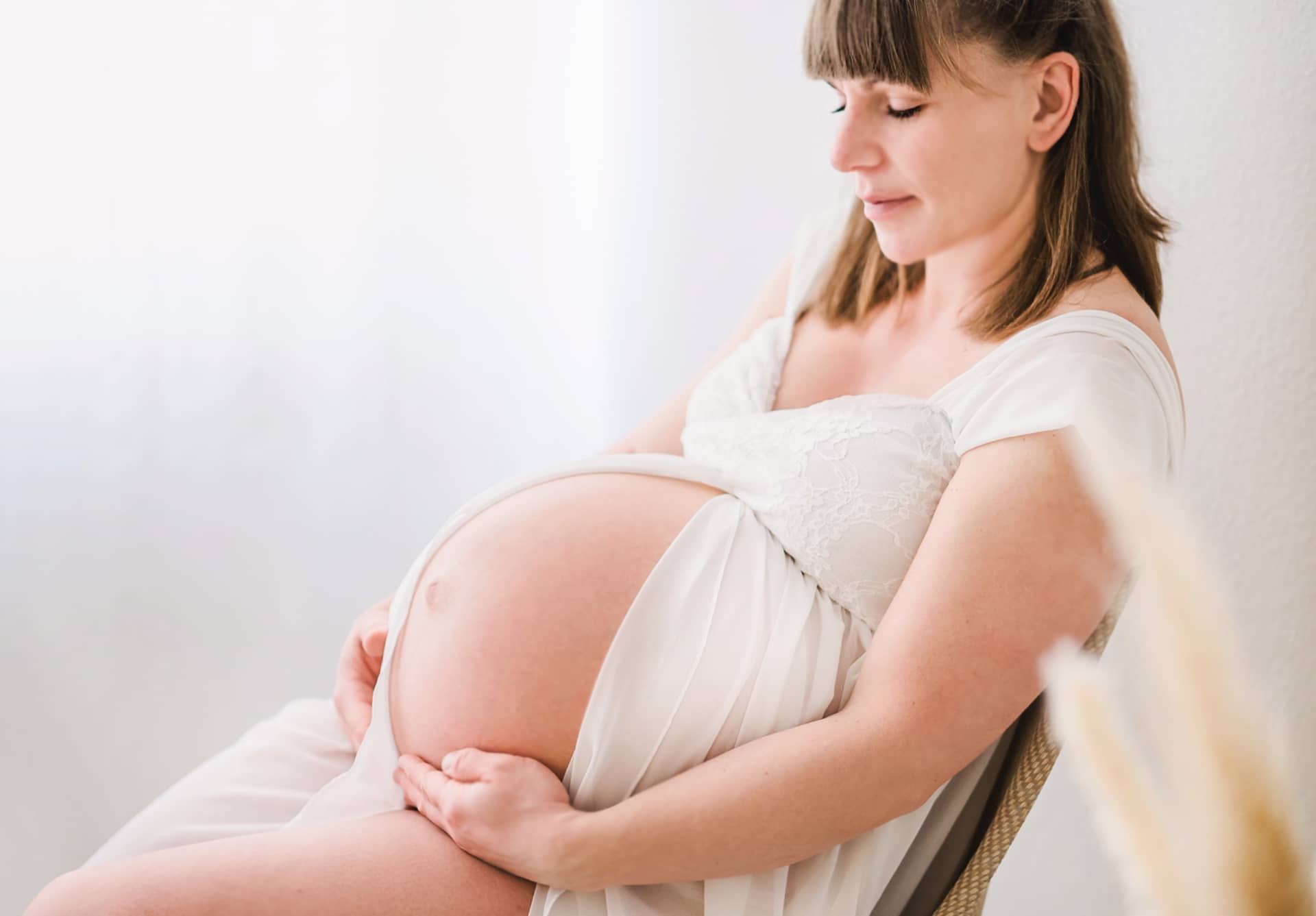 Babybauch Shooting - Sitzende schwangere Frau im Fotostudio