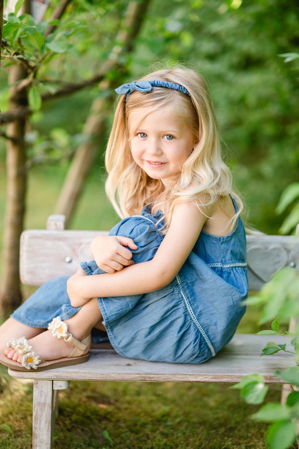 Kindergarten Mädchen sitzt auf kleiner Bank im Garten beim Kindergarten Fotoshooting